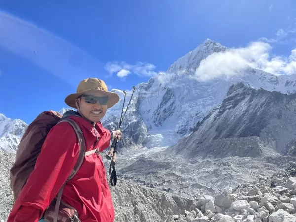 Man in climbing gear pointing towards the summit of Mt Everest from base camp.
