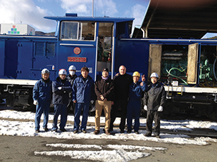 Members of the Hotstart Asia Pacific, Ltd. team in from of a locomotive.