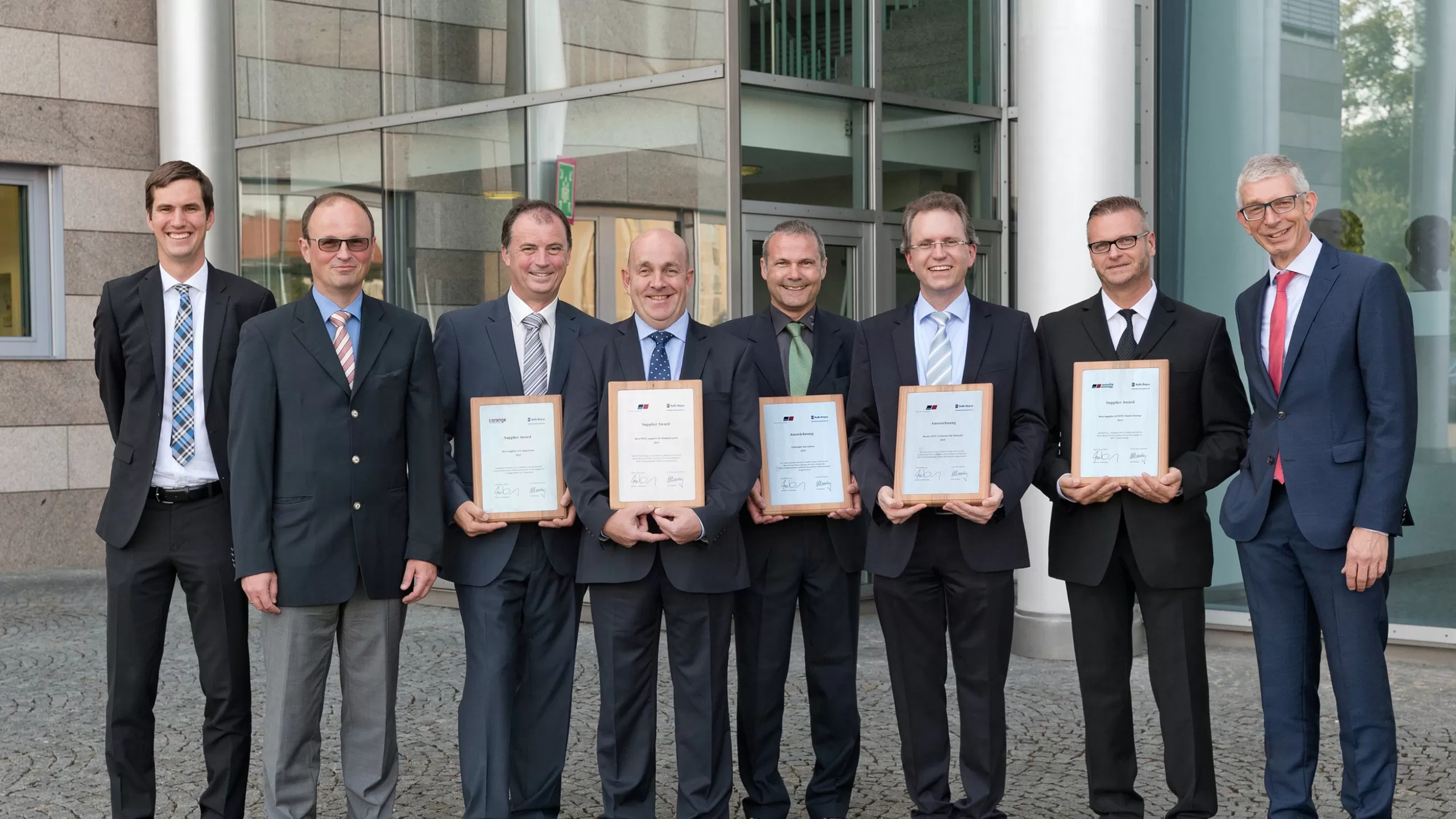 Group of people standing side by side holding plaques to indicate winning Supplier of the Year award from Rolls Royce MTU